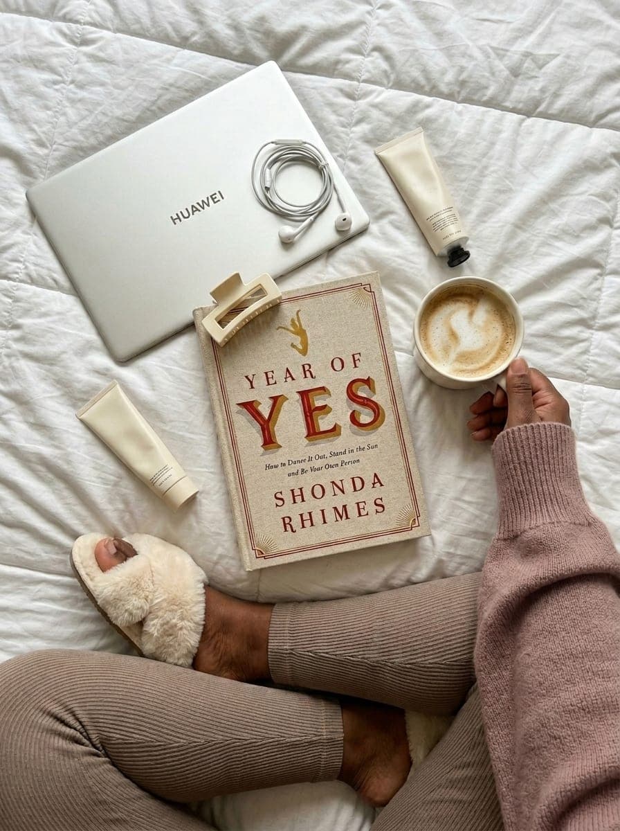 A calm lifestyle workspace with coffee, laptop, and a book on a bed