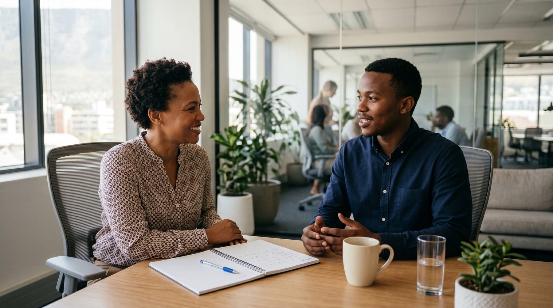 Two professionals in a bright office conversation about leadership and growth